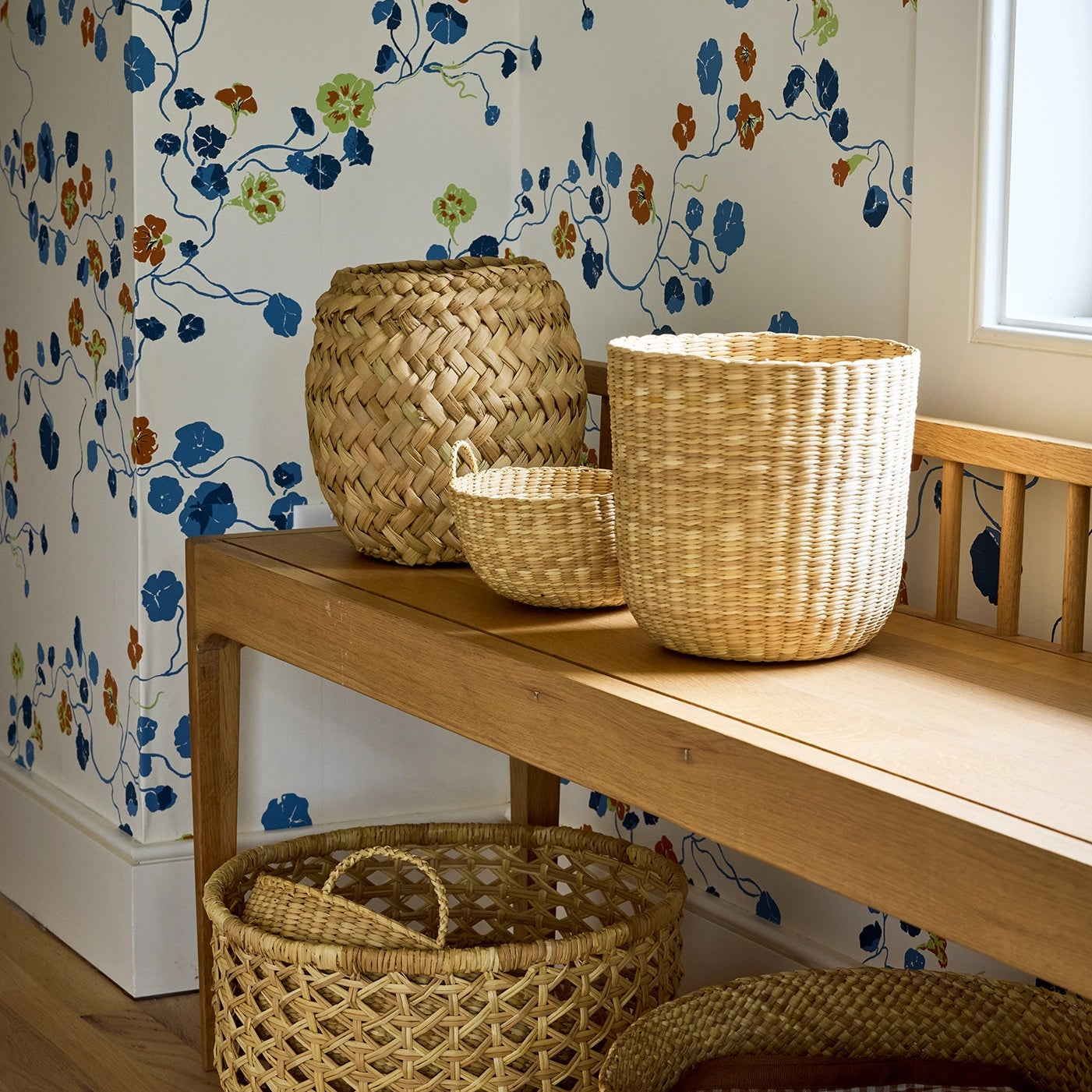 Intiearth Woven baskets on a wooden bench against floral wallpaper