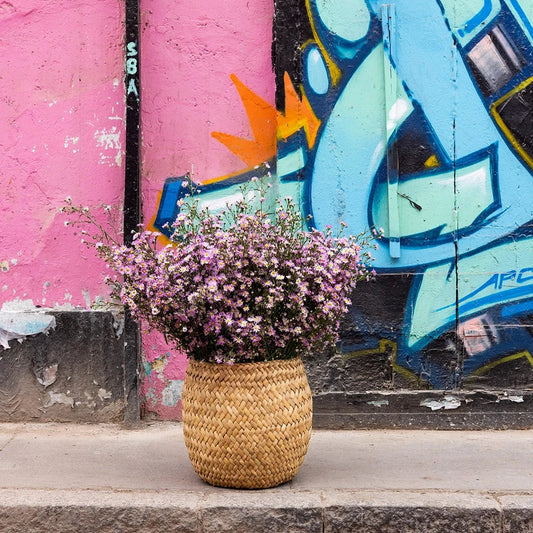 Flowers in an Intiearth Abeja Basket large made of totora in front of a colorful graffiti wall