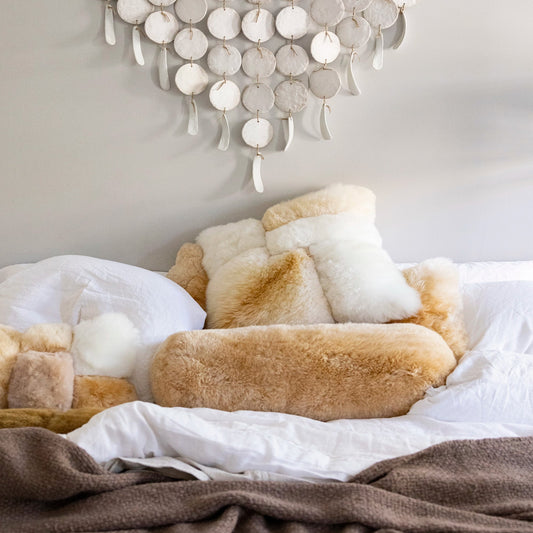 Cozy bedroom with alpaca pillows, blanket, and decorative wall hanging.