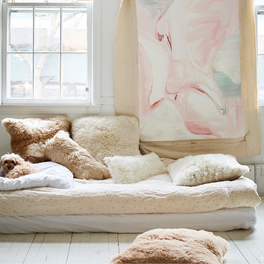 Cozy bedroom with a large floral tapestry, soft alpaca pillows, and a dog on a bed.