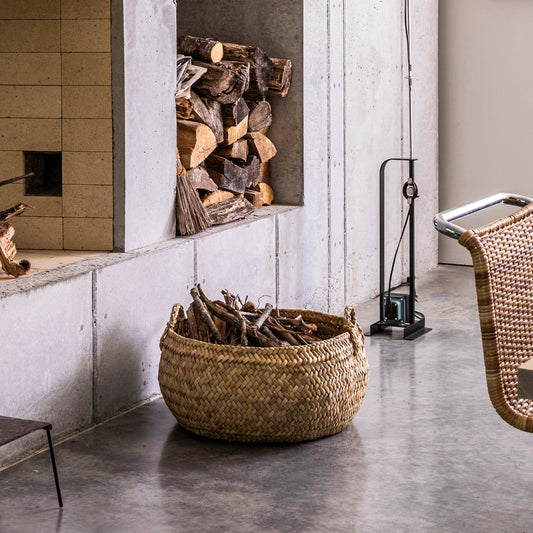 Wicker basket with firewood next to a fireplace in a modern room.