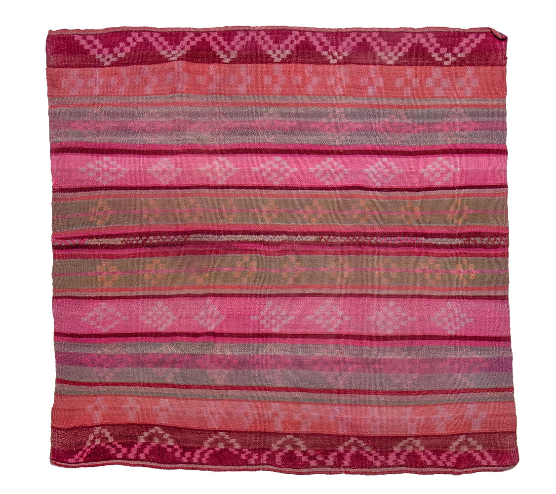 A square woven textile with horizontal stripes and geometric patterns in shades of pink, coral, burgundy, and muted taupe, photographed flat against a plain white background.