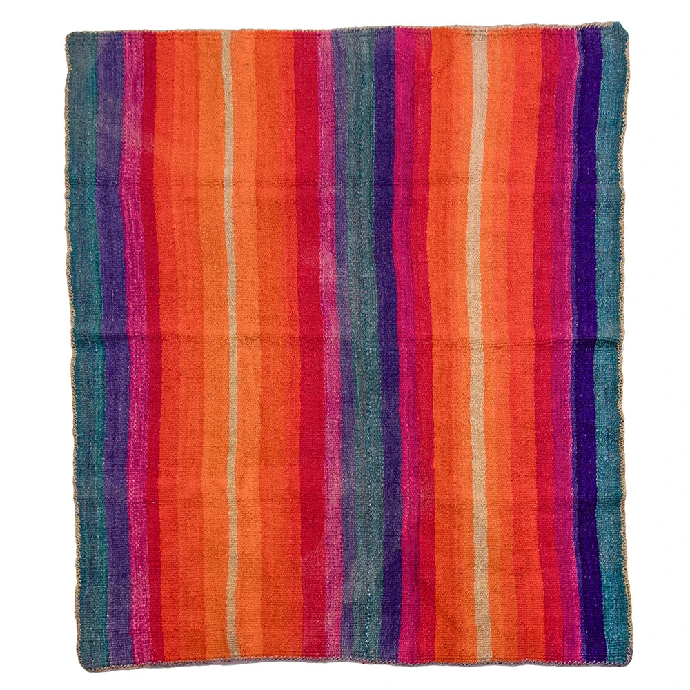 A square woven textile with vertical multicolor stripes in orange, red, pink, purple, blue, and beige, laid flat against a white background.