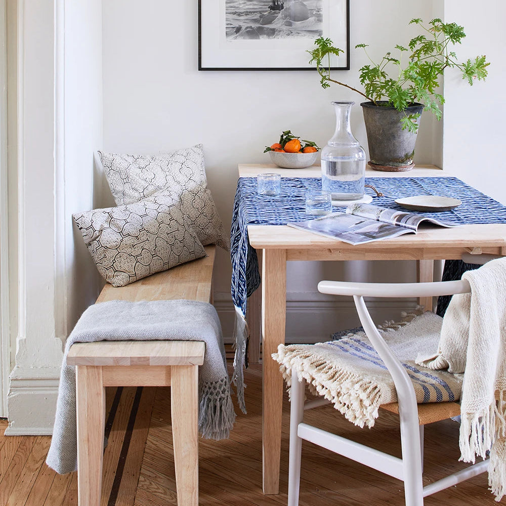 Dining room with wooden table, chairs, and bench, featuring framed artwork on the wall.