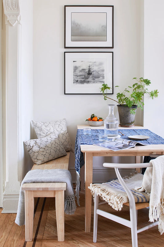 Dining room with wooden table, chairs, and bench, featuring framed artwork on the wall.