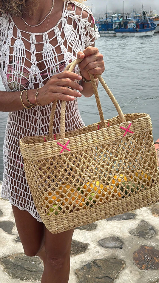Person holding a woven bag with a scenic background