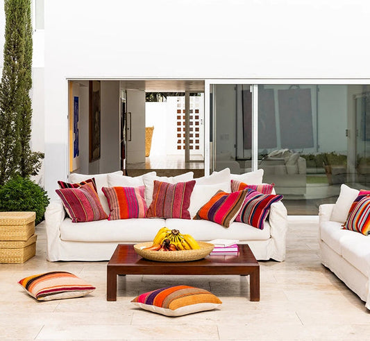 Modern outdoor patio with white sofas, colorful cushions, and a wooden coffee table.
