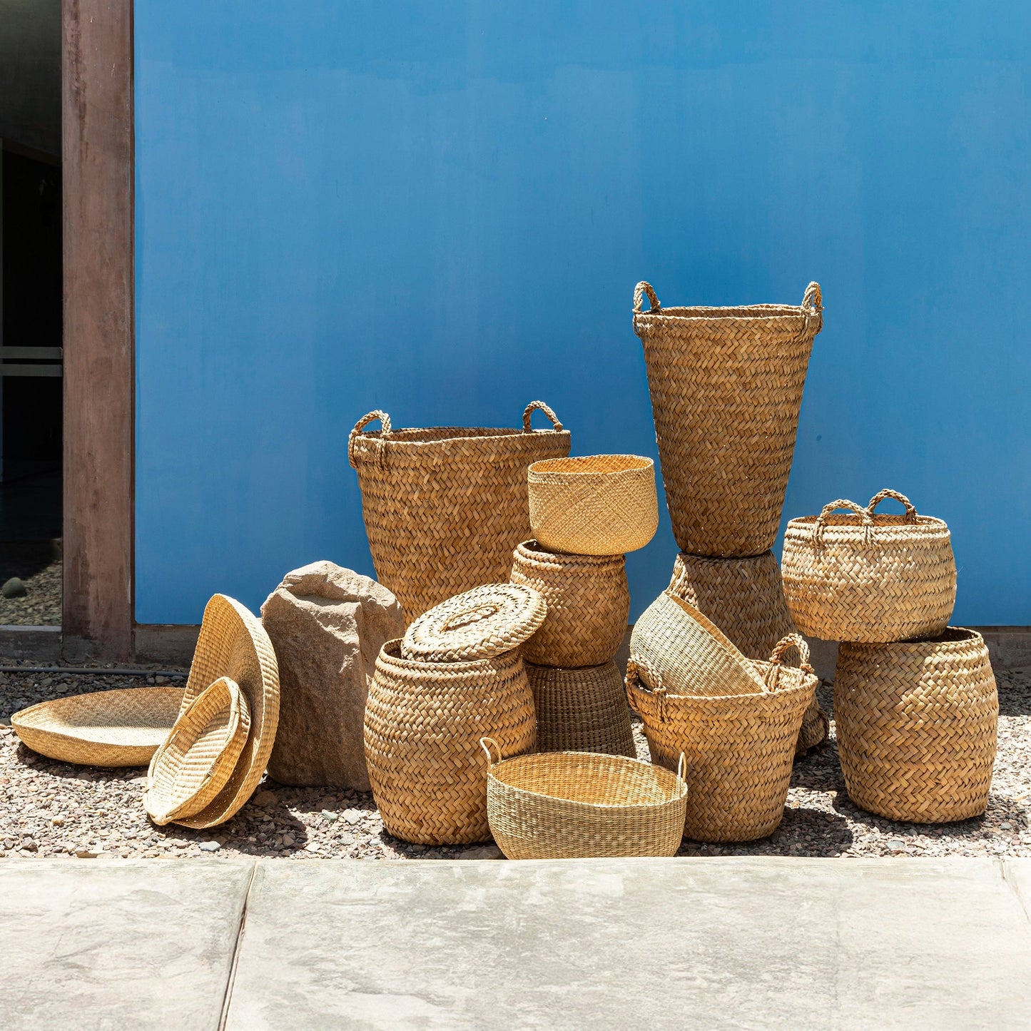 Collection of wicker baskets of various sizes against a blue wall.