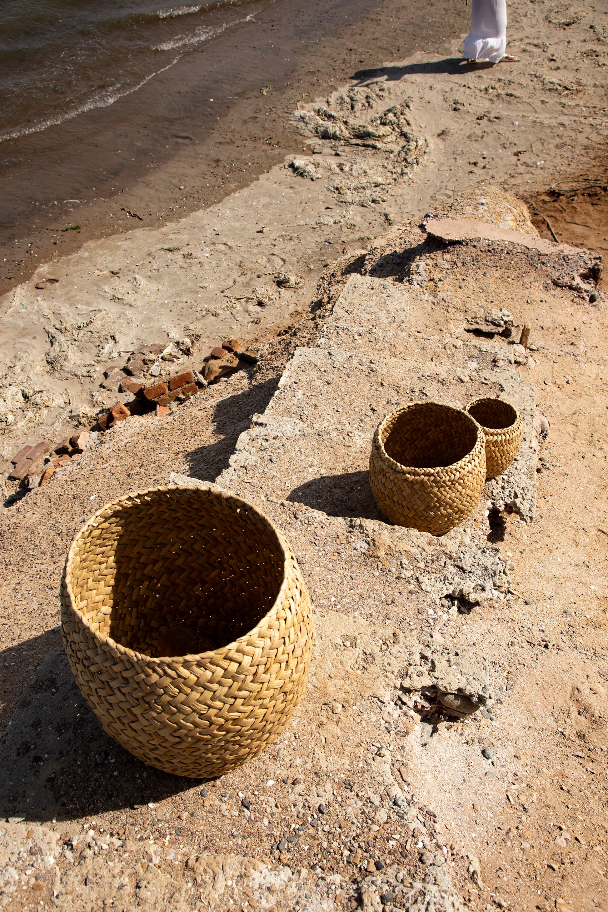 Woven baskets on a sandy surface near water
