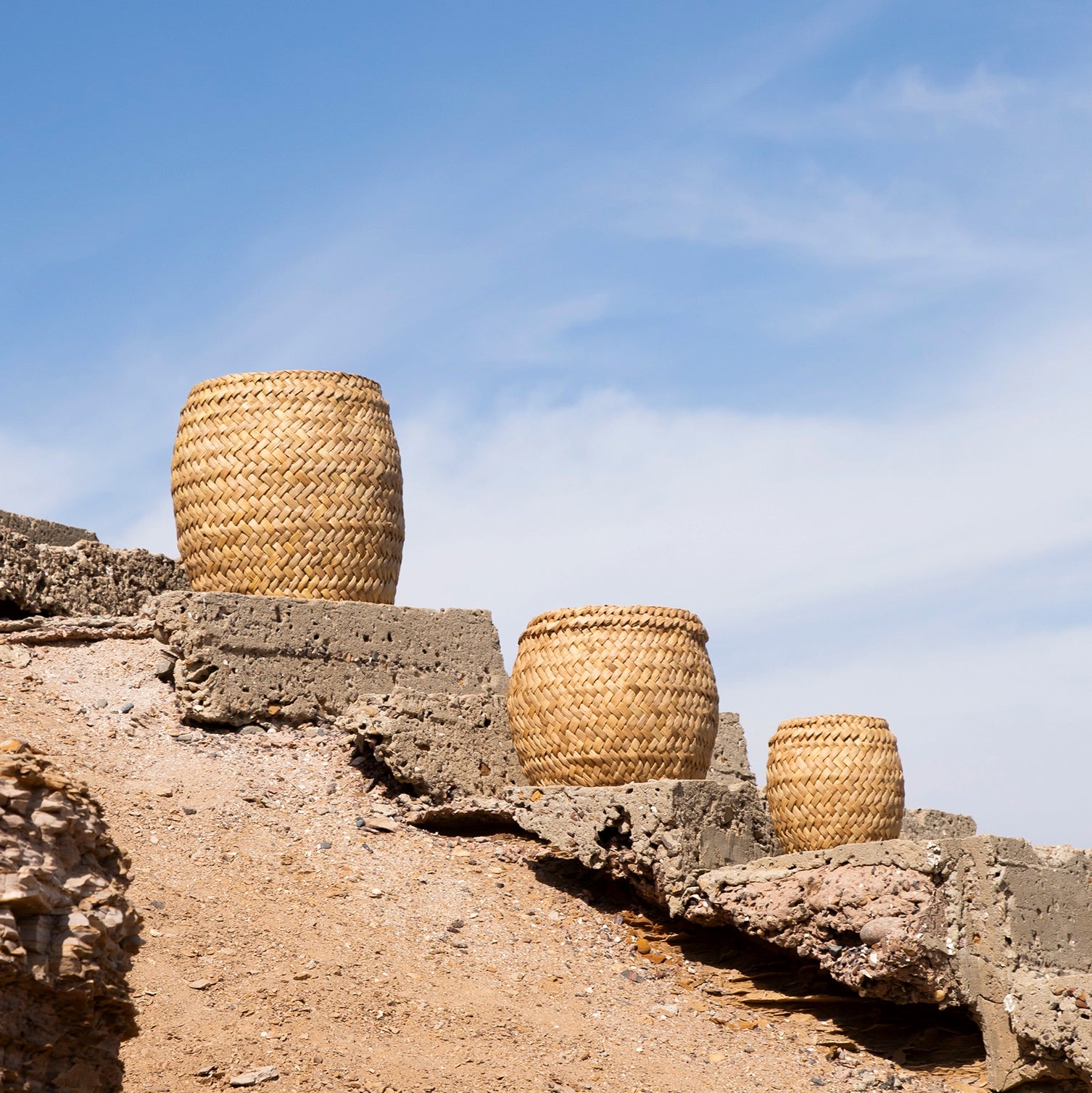 Three woven baskets on stone steps with a clear blue sky.