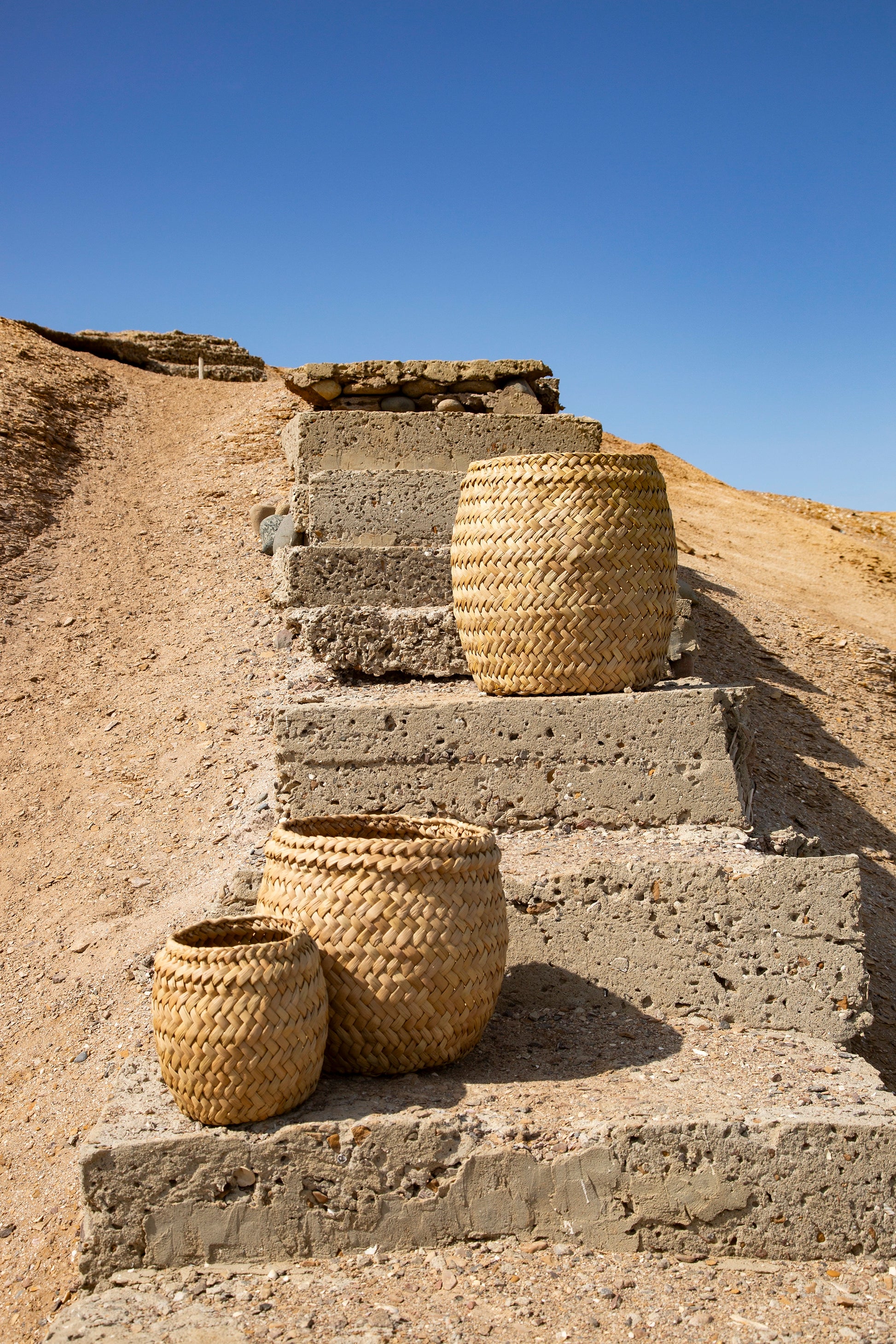 Woven baskets on stone steps against a clear blue sky