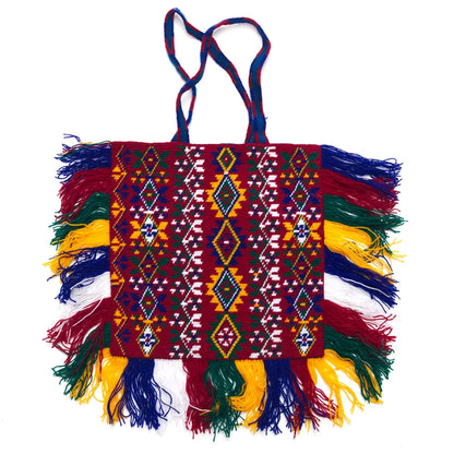 Colorful handbag with geometric patterns and fringes on a white background