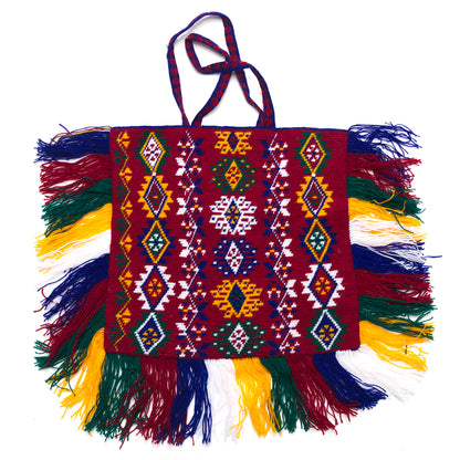 Colorful handbag with intricate patterns and fringes on a white background