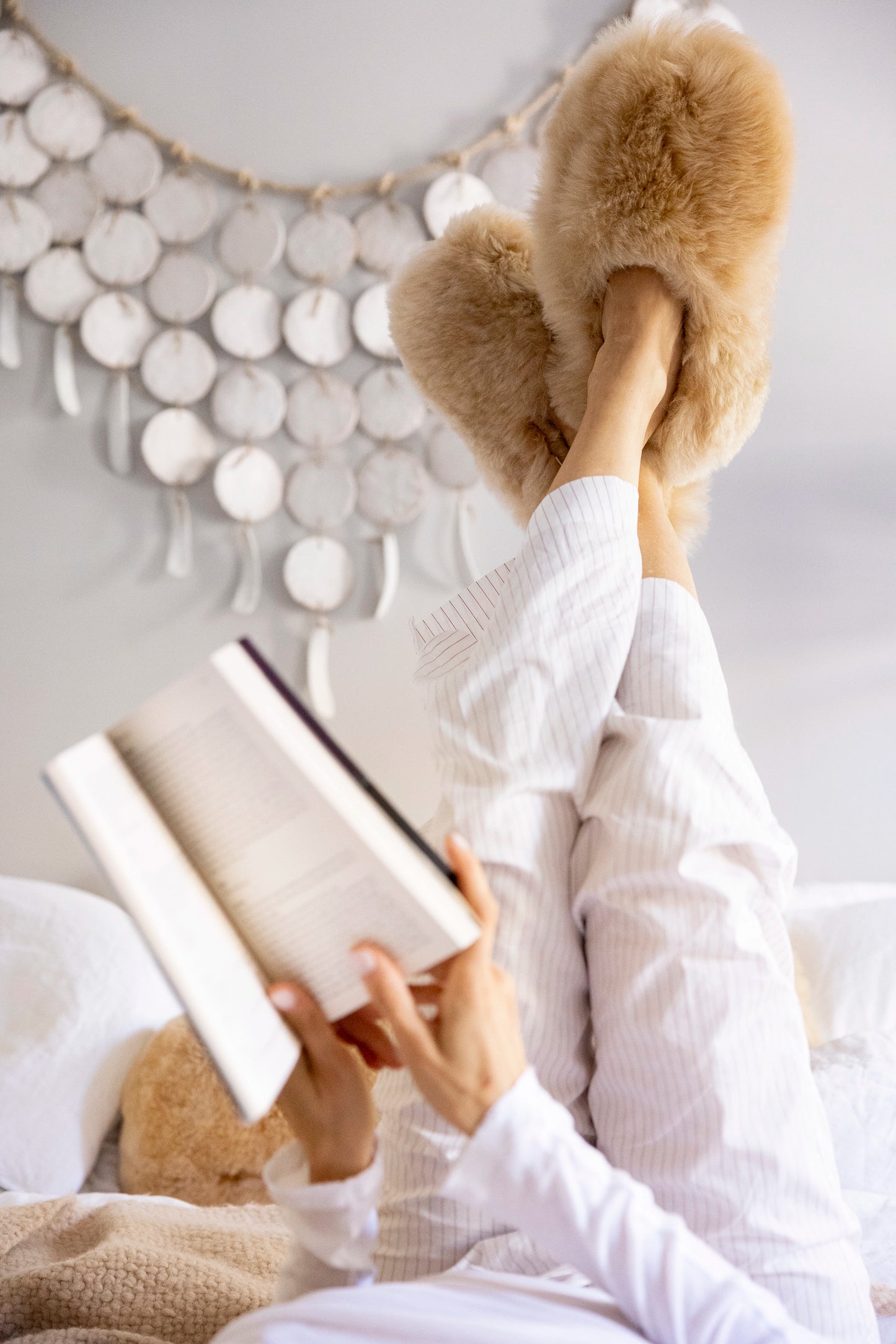 Intiearth Champagne-colored alpaca fur slippers featuring plush fur uppers, soft suede soles, and warm sheepskin insoles on woman reading in bed