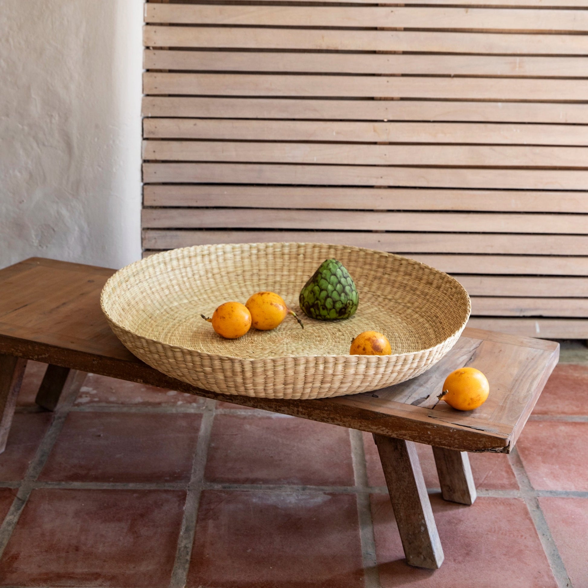 Intiearth Handwoven oversized basket platter made of natural fibers, ideal as a serving dish or decorative centerpiece on stool