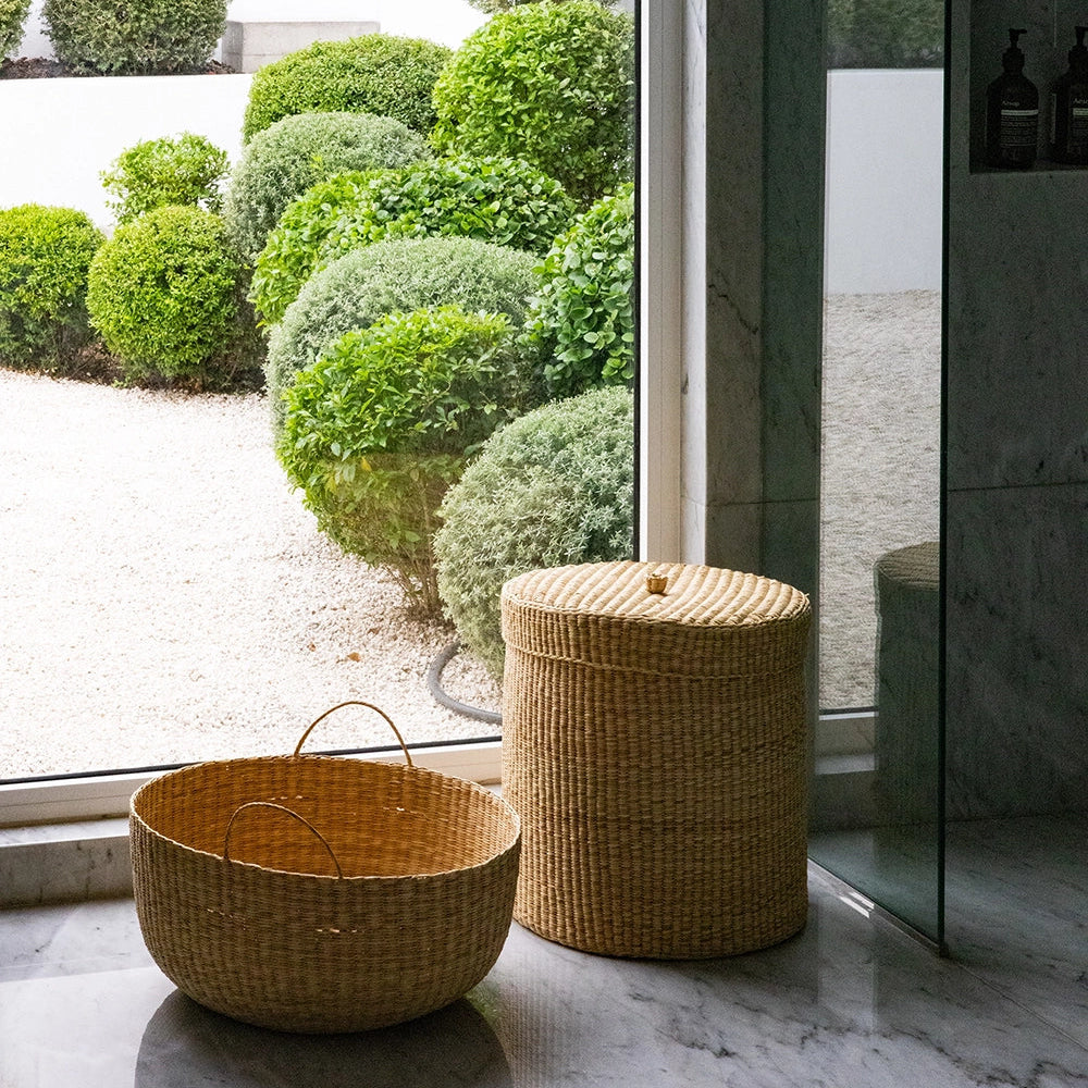 Wicker baskets on a stone surface with a garden view through a glass door.