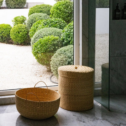 Wicker baskets on a stone surface with a garden view through a glass door.