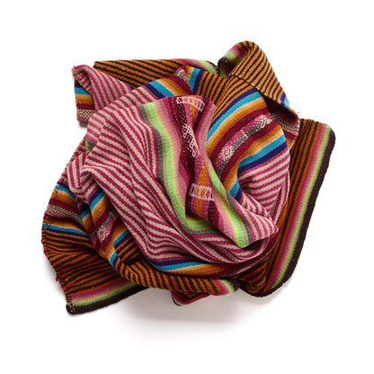 A multicolor striped woven textile, likely a traditional Peruvian blanket or scarf, featuring stripes of pink, red, green, blue, orange, and brown on a white background.