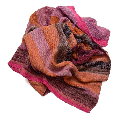 A multicolor striped knit scarf with shades of pink, orange, brown, and purple, styled in soft folds on a white background.