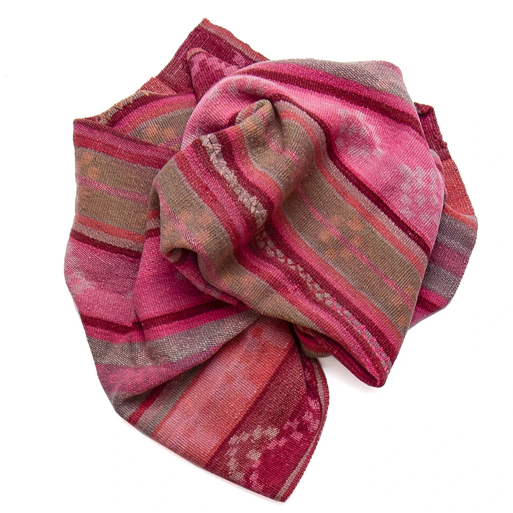 A folded patterned scarf in shades of pink, red, and brown with woven geometric stripes, shown on a plain white background.