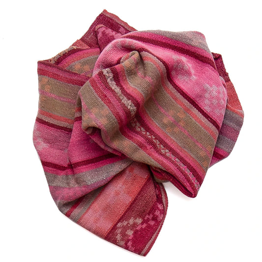 A folded patterned scarf in shades of pink, red, and brown with woven geometric stripes, shown on a plain white background.