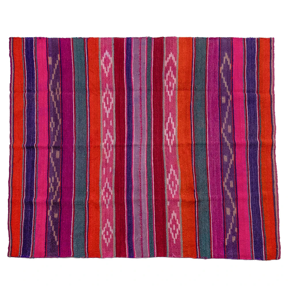 A rectangular woven textile rug with vertical stripes and geometric diamond motifs in bright pink, red, orange, purple, teal, and cream, shown flat against a white background.