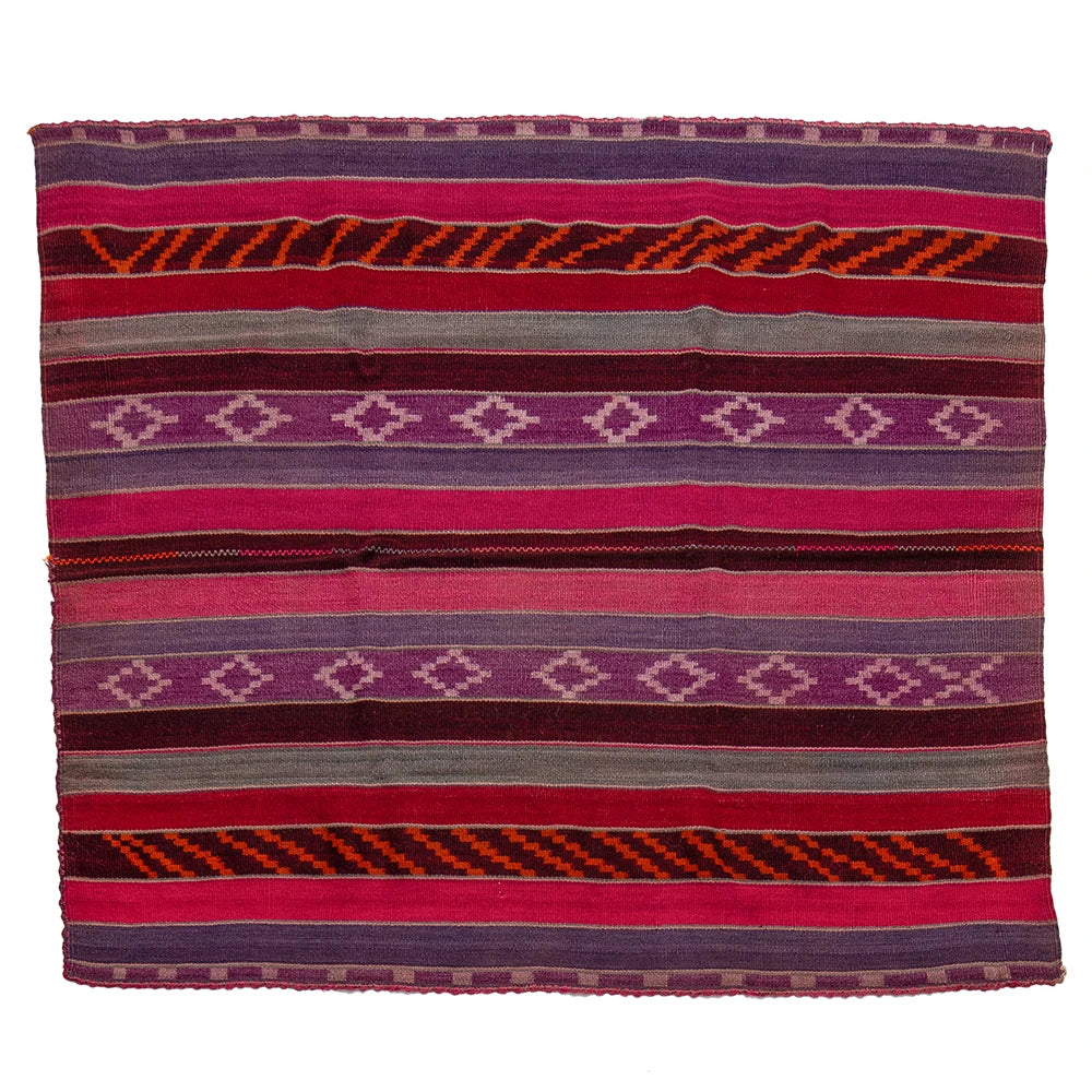A square woven textile blanket with horizontal stripes and geometric diamond patterns in shades of pink, purple, red, orange, and gray, shown flat against a white background.