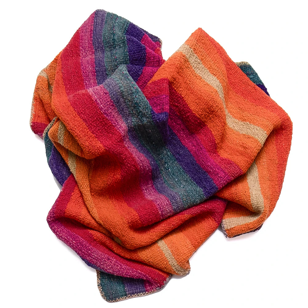 A folded multicolor striped scarf with textured stripes of orange, pink, purple, teal, and beige on a white background.