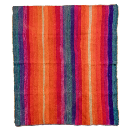 A square woven textile with vertical multicolor stripes in orange, red, pink, purple, blue, and beige, laid flat against a white background.