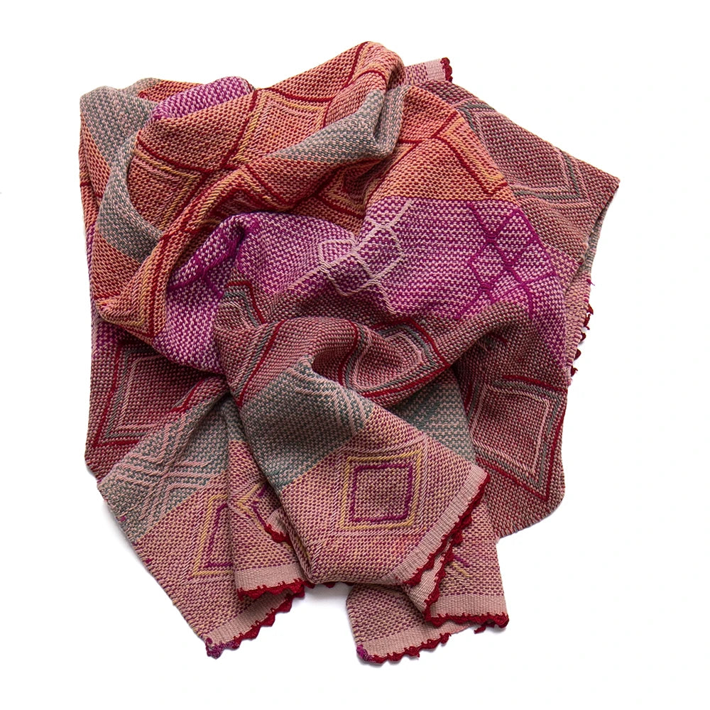 Folded patterned fabric with pink, red, and brown colors on a white background
