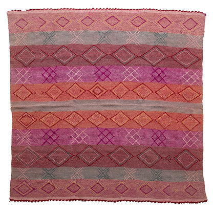 Woven textile with geometric pattern in shades of pink, purple, and red on a white background
