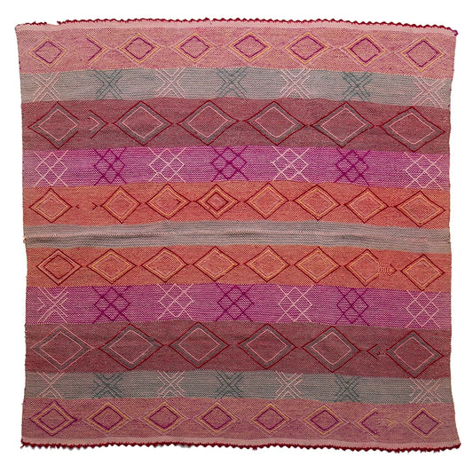 Woven textile with geometric pattern in shades of pink, purple, and red on a white background