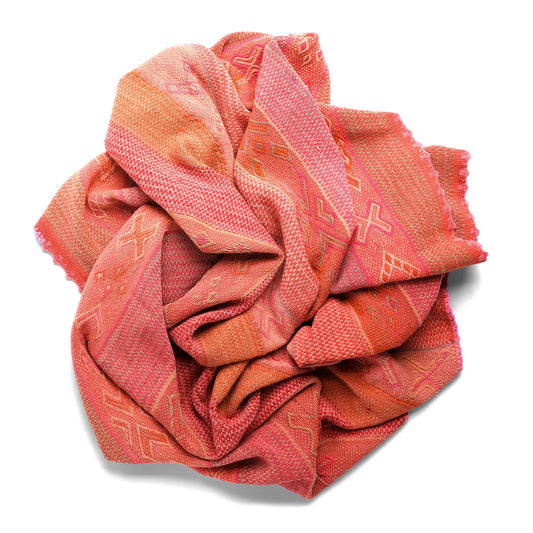 Folded pink and orange patterned frazada  on a white background