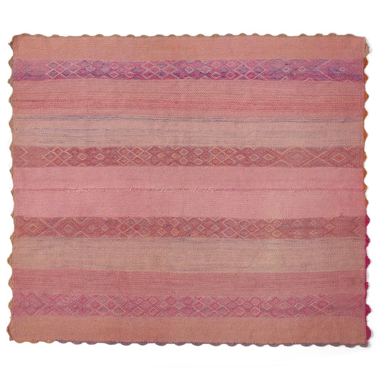 A square handwoven kilim rug in shades of pink, terracotta, and beige, featuring horizontal stripes with diamond and geometric patterns and a scalloped edge.