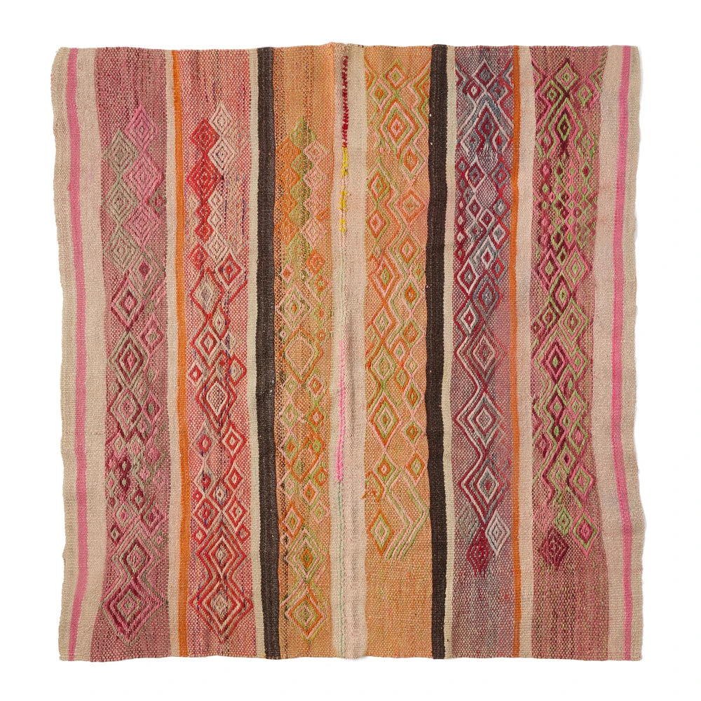 A square woven kilim rug with vertical stripes and diamond geometric patterns in pink, orange, brown, beige, and red, shown flat against a white background.