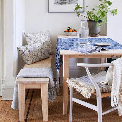 Dining room with wooden table, chairs, and bench, featuring framed artwork on the wall.