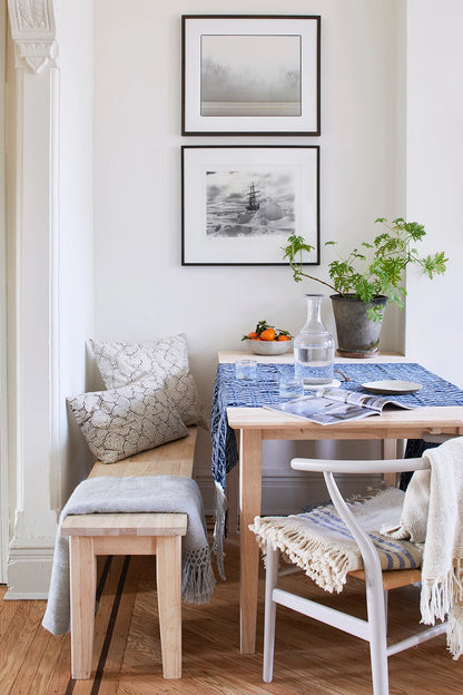 Dining room with wooden table, chairs, and bench, featuring framed artwork on the wall.