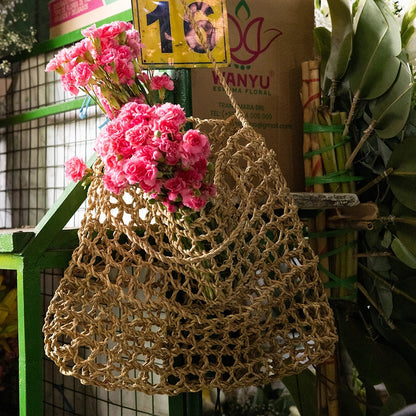 Intiearth Playa woven  bag with pink flowers and a cardboard box labeled '16' in an outdoor setting.