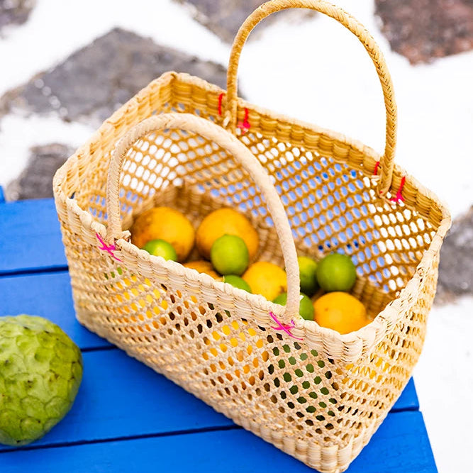 Woven basket with fruits on a blue surface and stone pavement background