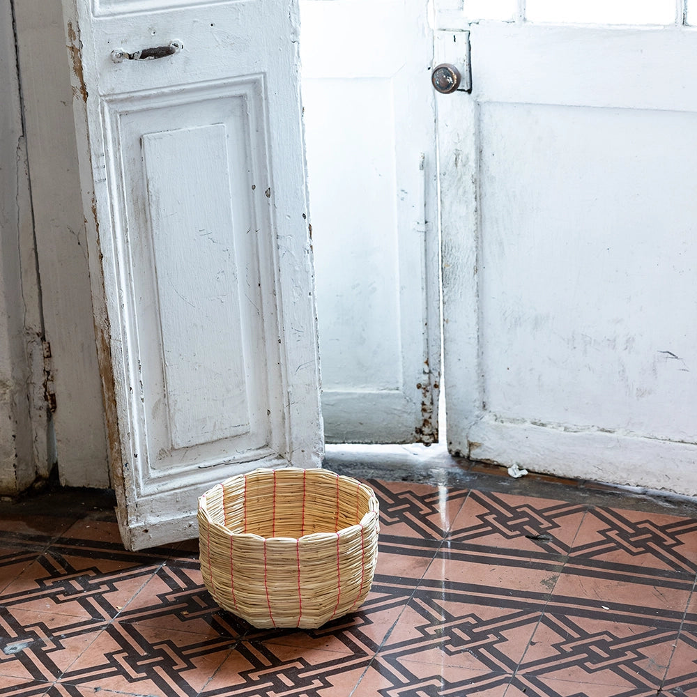 Intiearth Puno Woven basket on a patterned floor with a white door in the background