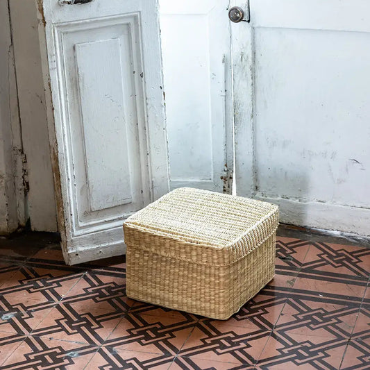 Intiearth Reed Storage Basket Box with lid on painted cement tile floor with a white door in the background