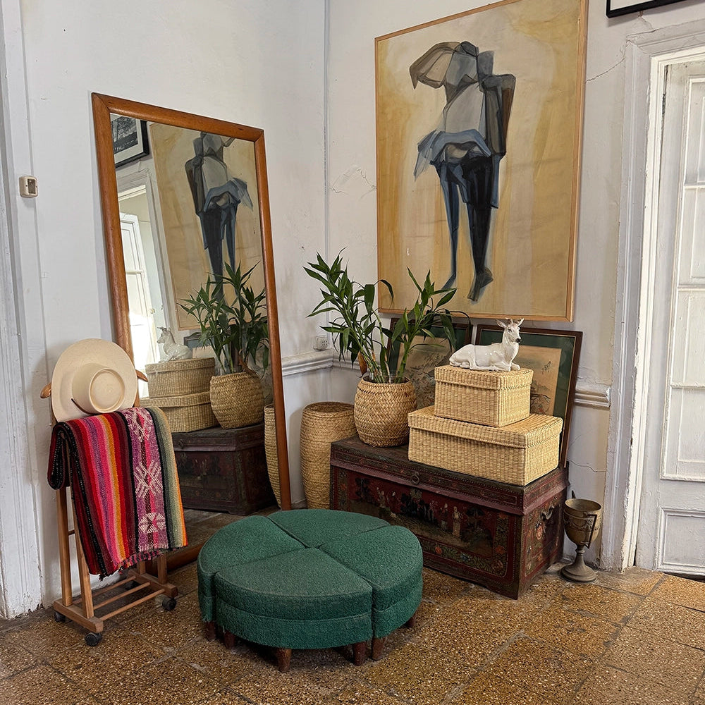 Room interior with a large mirror, ottoman, woven basket storage boxes stacked, and decorative items.