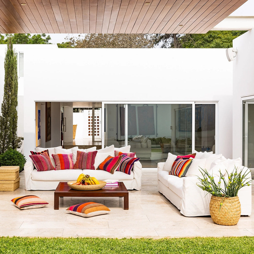 Modern outdoor patio with white sofas, colorful cushions, and a wooden coffee table.