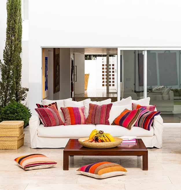 Modern outdoor patio with white sofas, colorful cushions, and a wooden coffee table.