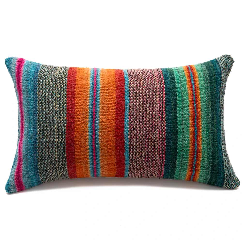 A rectangular lumbar throw pillow with a vibrant, multicolored serape-style striped pattern, featuring vertical bands of teal, orange, red, pink, and green on a clean white background.
