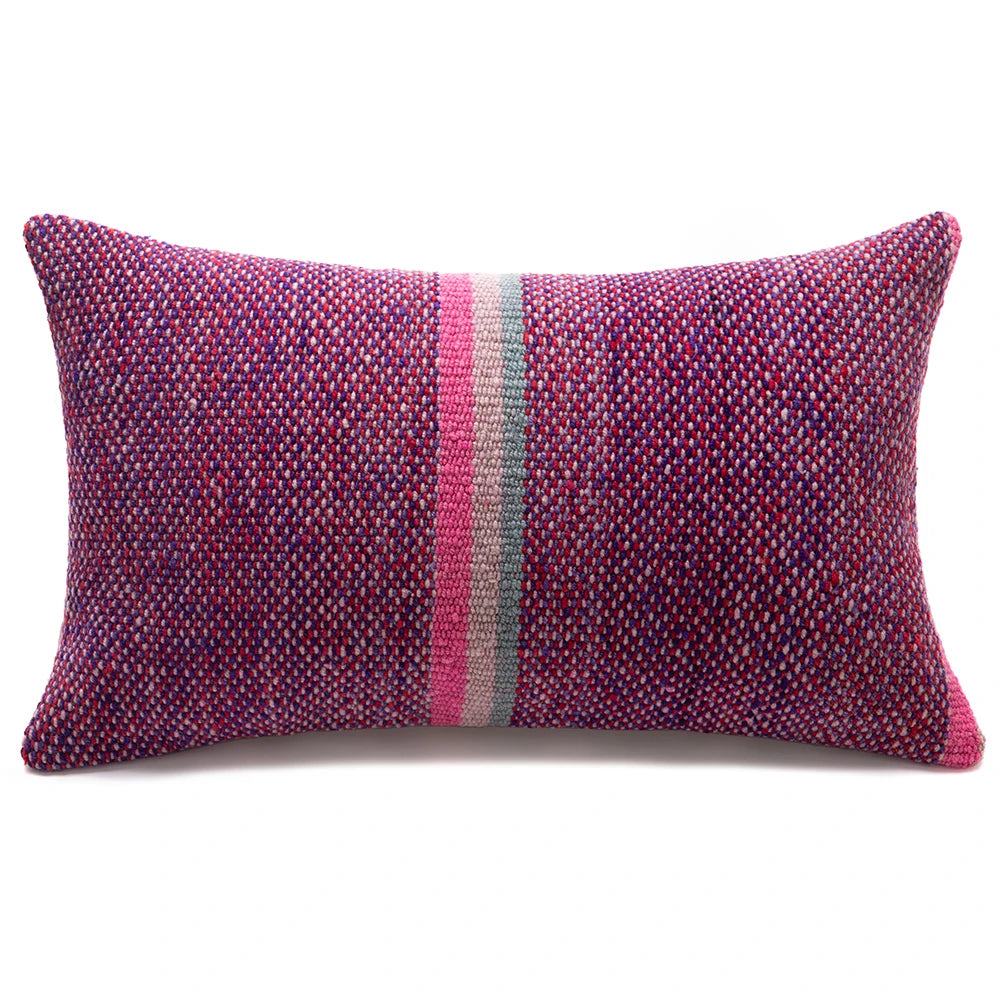 A rectangular woven throw pillow with a textured multicolor pattern of pink, purple, and blue threads, featuring a central vertical stripe of pink, gray, and white, set against a plain white background.