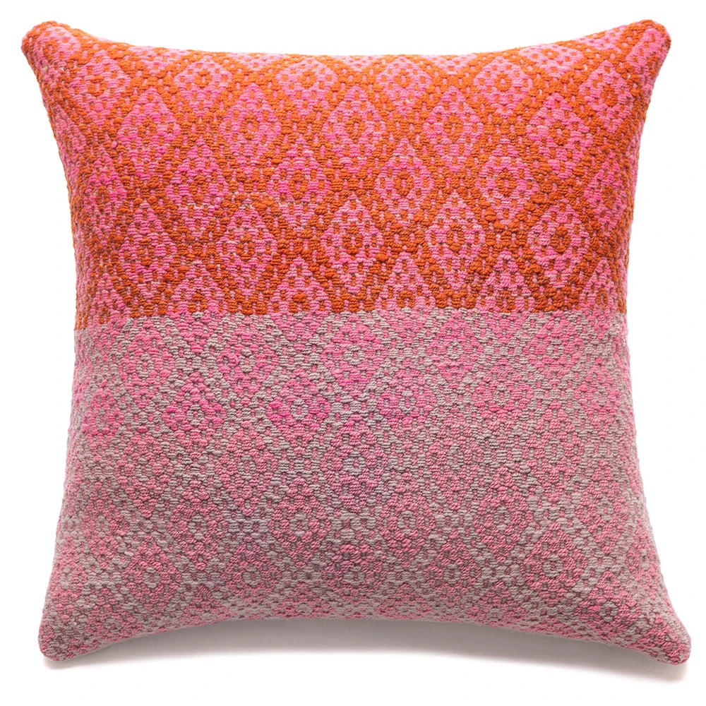 A square decorative throw pillow with a woven geometric pattern, featuring a vibrant orange and pink top half and a textured pink and gray bottom half, set against a plain white background.